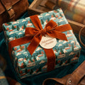Adventure camping gift wrap with mountains, tied with a rust velvet bow by Wrapped Studios.