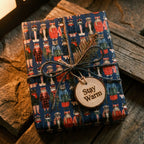 Christmas cat wrapping paper by Wrapped Studios on a gift tied with rustic twine and a "Stay Warm" tag.