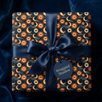 Celestial wrapping paper with a mystical sun and moon pattern, navy satin ribbon, by Wrapped Studios.