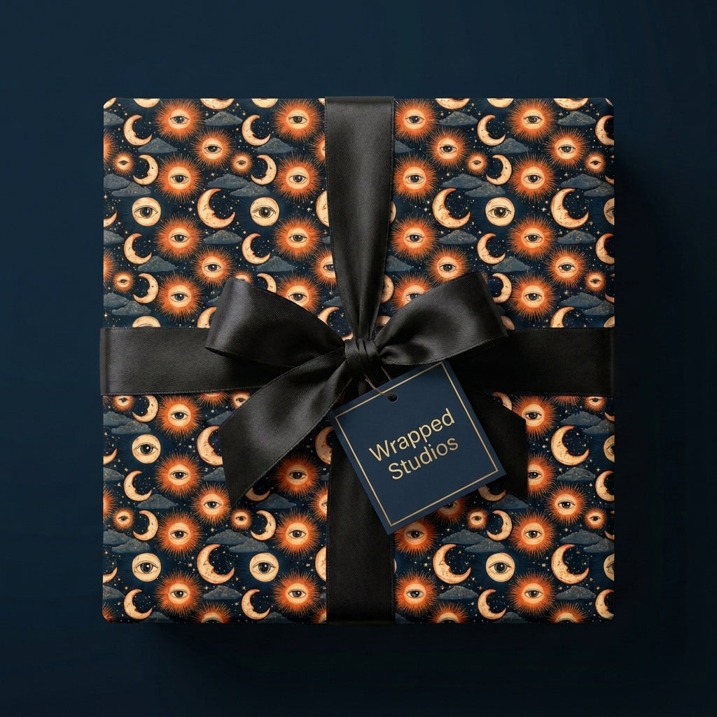 Celestial wrapping paper with a mystical sun and moon pattern, tied with a black satin bow by Wrapped Studios.