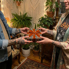 Tattooed hands exchange a gift in celestial moon wrapping paper with a velvet bow by Wrapped Studios.