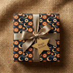 Celestial wrapping paper with mystical sun and moon pattern and gold ribbon by Wrapped Studios.
