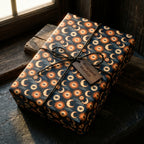 Mystical celestial wrapping paper with a sun and moon pattern on a gift box by Wrapped Studios.