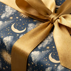 Celestial wrapping paper with vintage sun and moon pattern and a gold satin bow, by Wrapped Studios.