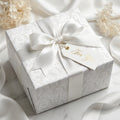 Elegant white damask wrapping paper on a luxury wedding gift with a satin bow and tag by Wrapped Studios.