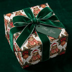 Whimsical frog Christmas wrapping paper by Wrapped Studios on a gift box with a luxury green velvet bow.