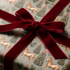Vintage Christmas wrapping paper with golden horses and a luxury red velvet bow by Wrapped Studios.