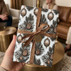 Luxury Christmas wrapping paper with pinecones and a bronze ribbon bow, by Wrapped Studios.