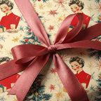 Vintage Christmas wrapping paper with retro lady pattern and a mauve satin ribbon bow.