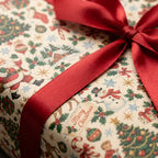 Vintage Christmas wrapping paper with retro Santa and snowman pattern and a red satin bow by Wrapped Studios.