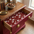 Vintage burgundy floral wrapping paper lining a wooden dresser drawer by Wrapped Studios.