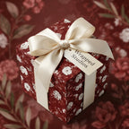 Luxury burgundy vintage floral wrapping paper on a gift box with a cream satin bow by Wrapped Studios.