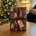 Red vintage Christmas wrapping paper with velvet ribbon by Wrapped Studios, on a cozy living room table.