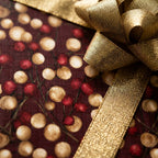 Luxury burgundy and gold berry Christmas wrapping paper with a metallic gold bow by Wrapped Studios.