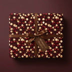 Luxury burgundy Christmas wrapping paper with gold berry pattern and brown ribbon by Wrapped Studios.