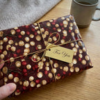 Elegant burgundy and gold Christmas wrapping paper with a gold bow and gift tag, by Wrapped Studios.
