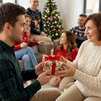Man gifting a present in vintage Christmas wrapping paper with a red bow. Wrapped Studios.