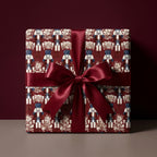Luxury nutcracker Christmas wrapping paper on a gift box with a burgundy satin bow by Wrapped Studios.