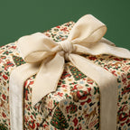 Vintage Christmas wrapping paper with Santa illustrations and a cream velvet ribbon bow by Wrapped Studios.