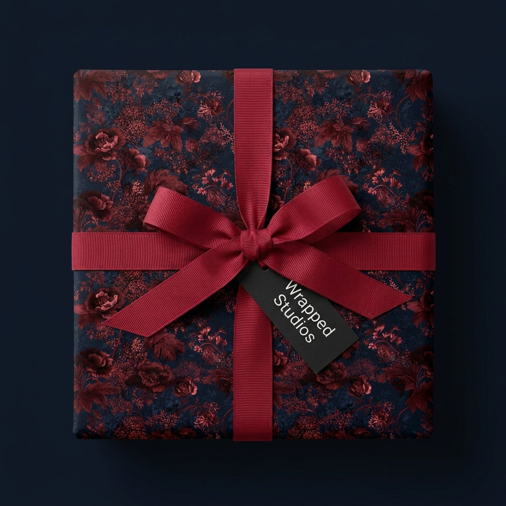 Luxury moody floral wrapping paper in burgundy and navy with a red bow by Wrapped Studios.
