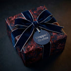 Luxury dark floral wrapping paper with a navy blue velvet bow and gift tag by Wrapped Studios.