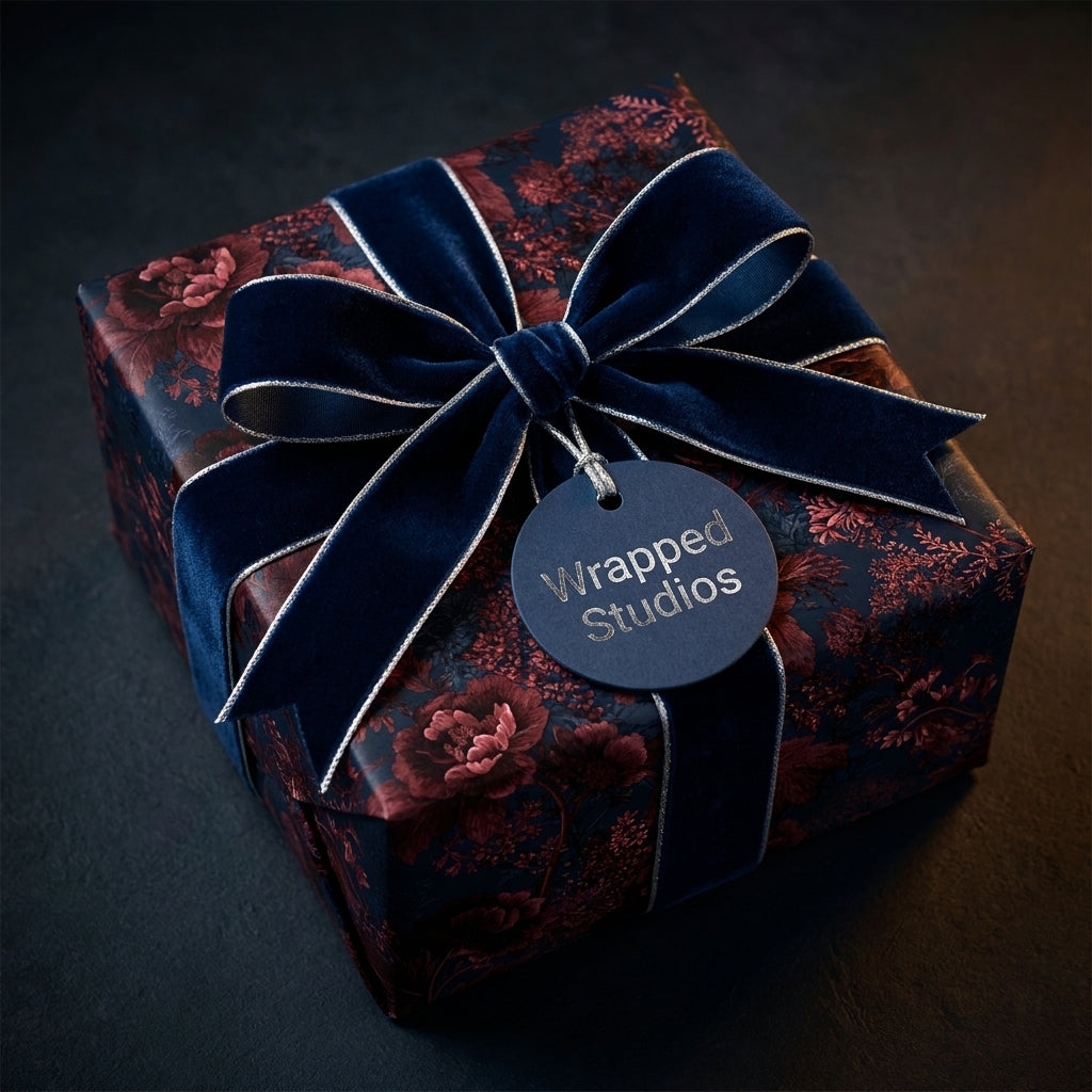 Luxury dark floral wrapping paper with a navy blue velvet bow and gift tag by Wrapped Studios.