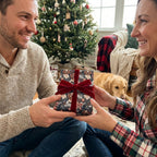 Couple exchanging gift in dog Christmas wrapping paper with red velvet bow by Wrapped Studios.