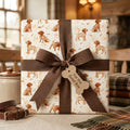 Dog wrapping paper with watercolor puppy print, brown ribbon, and bone tag by Wrapped Studios.