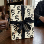 Black and cream dragon wrapping paper with a luxury black ribbon bow by Wrapped Studios.