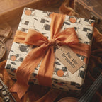 Drum kit wrapping paper with a terracotta silk bow and 'For the Drummer' tag by Wrapped Studios.