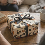 Vintage drum kit gift wrap with a black ribbon on a cozy wooden table by Wrapped Studios.