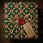 Luxury green and gold Christmas wrapping paper with a red wax seal and twine bow by Wrapped Studios.