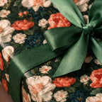 Moody floral wrapping paper with coral roses and a green satin ribbon by Wrapped Studios.
