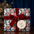 Elegant floral wrapping paper with a red velvet bow and 'With Love' tag by Wrapped Studios.