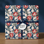 Luxury vintage floral wrapping paper with red roses and navy ribbon on a gift box by Wrapped Studios.