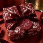 Elegant burgundy floral Christmas gift wrap with a red velvet ribbon by Wrapped Studios.
