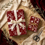 Luxury burgundy floral wrapping paper on holiday gift boxes with satin ribbons by Wrapped Studios.