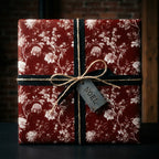 Vintage burgundy floral Christmas wrapping paper with a black ribbon and Noel tag by Wrapped Studios.