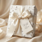 Elegant cream floral wrapping paper with a luxury satin bow and 'With Love' tag by Wrapped Studios.