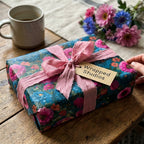 Elegant botanical floral wrapping paper with a pink ribbon and gift tag from Wrapped Studios.