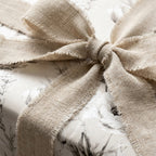 Vintage floral wrapping paper with a rustic frayed linen bow on a luxury gift box by Wrapped Studios.