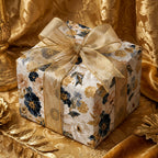 Luxury navy and gold floral wrapping paper with a sheer gold bow on a gift box by Wrapped Studios.
