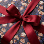 Vintage cinema gift wrap featuring a retro popcorn pattern and burgundy satin bow by Wrapped Studios.