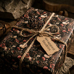 Vintage dark floral wrapping paper with rustic twine and Wrapped Studios tag for elegant gift wrapping.