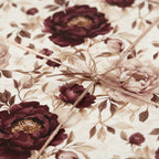 Elegant floral wrapping paper with burgundy peony print and metallic gold ribbon bow.