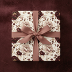 Elegant floral wrapping paper on square gift box with matching dusty rose ribbon and bow.