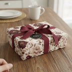 Elegant floral wrapping paper with burgundy ribbon on a wrapped gift box.
