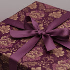 Close-up of a gift wrapped in luxury floral wrapping paper with a silky purple ribbon.