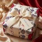 Vintage floral wrapping paper with burgundy flowers, cream bow, and 'With Love' tag by Wrapped Studios.