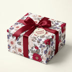 Vintage floral wrapping paper with a burgundy ribbon on a luxury gift box by Wrapped Studios.